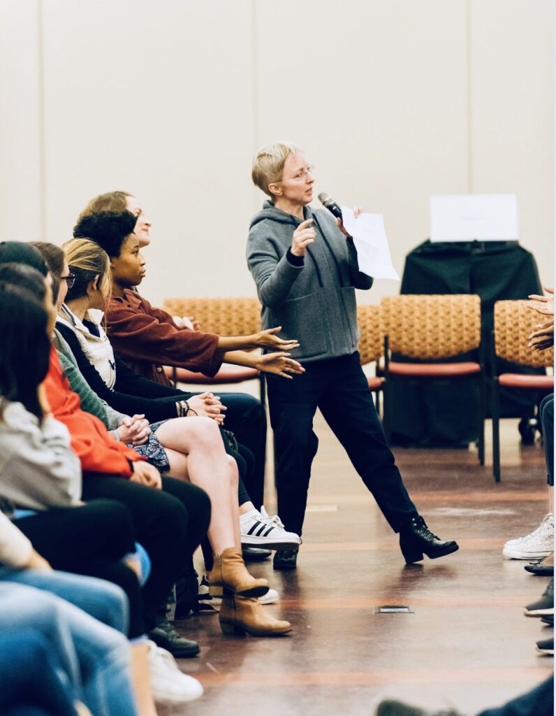 People interacting in a workshop, gesturing and speaking.